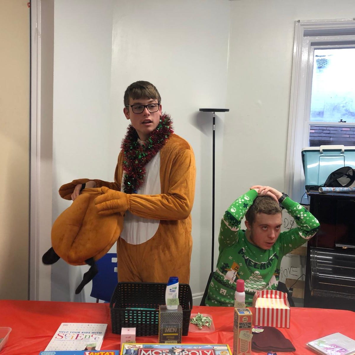 Two boys dressed in festive costumes, smiling and enjoying a lively Christmas party atmosphere.